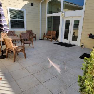 A sunny patio with outdoor furniture including chairs, a table, and benches.