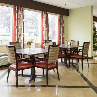 A spacious dining area with neatly arranged tables and chairs, featuring large windows with colorful curtains.