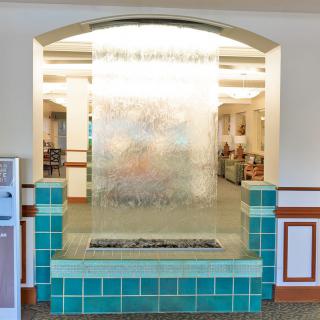 A decorative indoor water feature with cascading waterfall, surrounded by tiled accents in a public space.