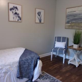 A serene spa room with a massage bed, decorated with calming artwork and cozy furnishings.