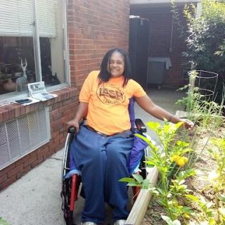 A joyful individual enjoying the beauty of gardening while seated in a wheelchair.