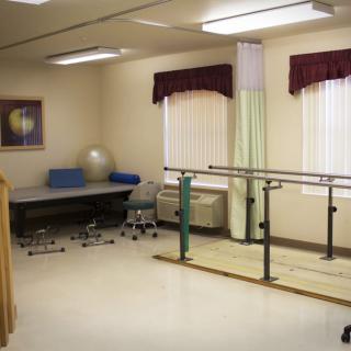 A physical therapy room equipped with parallel bars and exercise equipment.