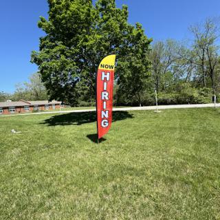 A vibrant 'Hiring' sign stands tall on a sunny day, signaling job opportunities in the area.