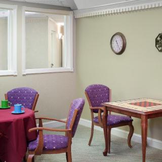 A cozy room with tables and chairs, featuring a wall clock and a window.