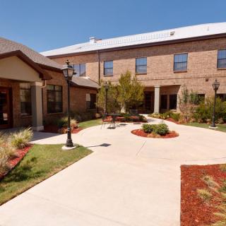 A sunny courtyard with landscaping and a brick building exterior.