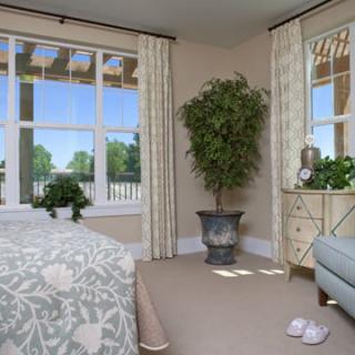 A cozy bedroom with large windows, potted plants, and elegant decor.
