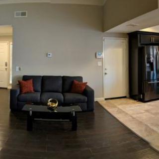 A modern living room with a dark sofa, red pillows, and a glass coffee table.