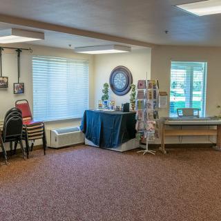 A cozy waiting room with chairs, a large wall clock, and a brochure stand.