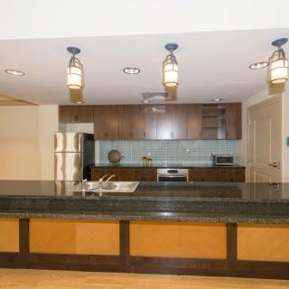 Modern kitchen with wood cabinets and pendant lighting.