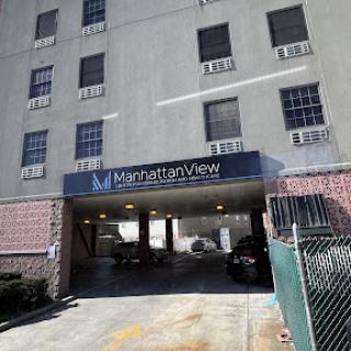 Entrance to a residential building with visible parking area and air conditioning units.