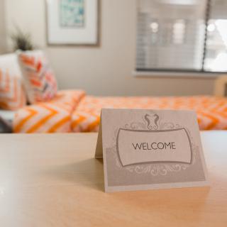 A welcoming card on a table in a cozy bedroom.