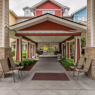 Covered entrance with seating area and landscaping.