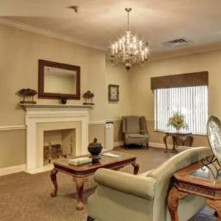 A cozy living room with elegant decor, featuring a chandelier, fireplace, and comfortable seating.