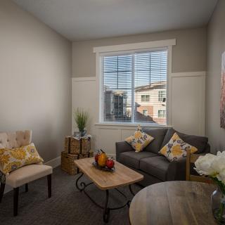 A cozy living room with a sofa, chairs, and a window letting in natural light.