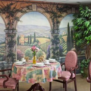 A cozy dining area with a beautifully set table, featuring a mural of a scenic landscape in the background.