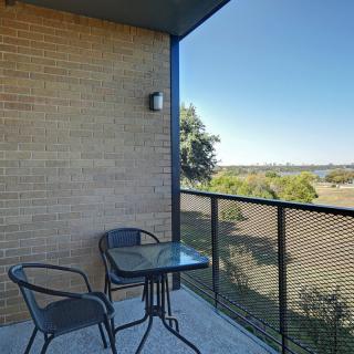 A balcony with two chairs and a glass table overlooking a scenic landscape.