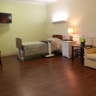 A well-organized hospital room with a bed, furniture, and a television.