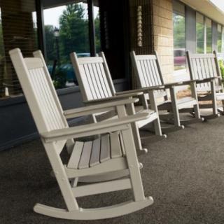A row of wooden rocking chairs on an outdoor porch.