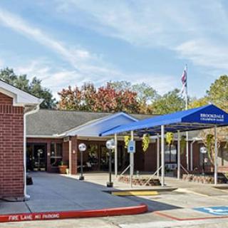 A building with a blue awning at the entrance next to a parking lot and an American flag.