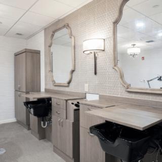 A modern salon interior featuring styling stations with mirrors, sinks, and chairs.