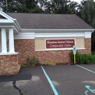 The entrance to the Roomba Senior Citizens Community Center, featuring a brick facade and designated parking.