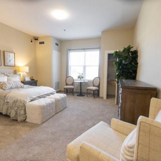 A cozy bedroom with a large bed, seating area, and natural light from a window.