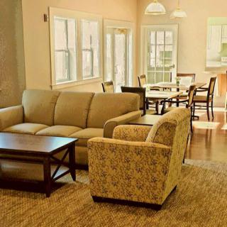A cozy living room with a sofa, armchair, and dining area.