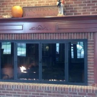A cozy fireplace with a wooden mantel and decorative items, set against a brick wall.