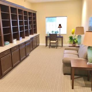 A cozy home office with a large bookshelf, a desk by the window, and a comfortable sofa.