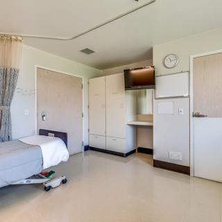 A clean and empty hospital room with a bed and medical equipment.