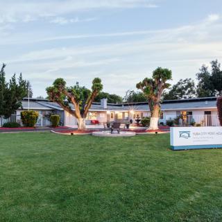 A spacious house with a well-maintained lawn and surrounding trees.