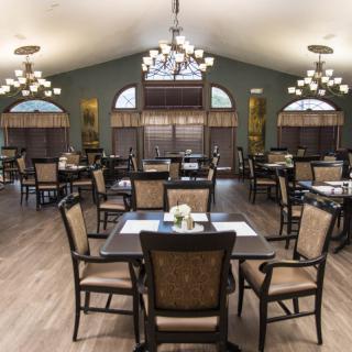 A spacious dining area with elegant chandeliers and neatly arranged tables and chairs.