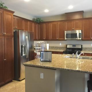 A modern kitchen with wood cabinets, stainless steel appliances, and granite countertops.