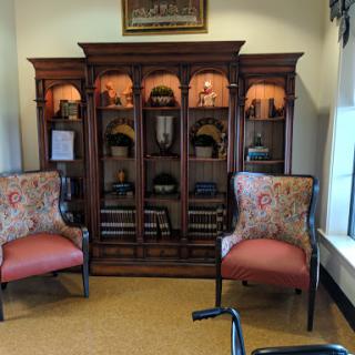 A cozy reading nook featuring elegant upholstered chairs and a wooden display cabinet.