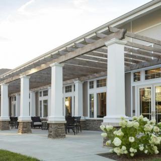 A modern building with large columns and a patio area featuring outdoor seating and flowers.