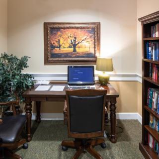 A cozy office space with a desk, laptop, and bookshelf.