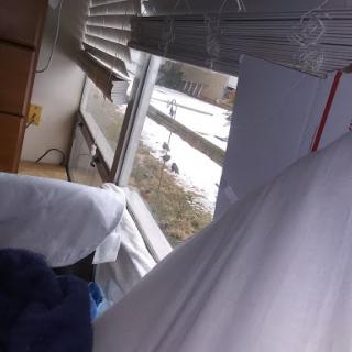 A glimpse of a snowy outdoor scene seen through a window from a cozy bedroom.