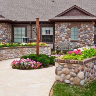 A beautifully landscaped house with a stone exterior and vibrant flower beds.