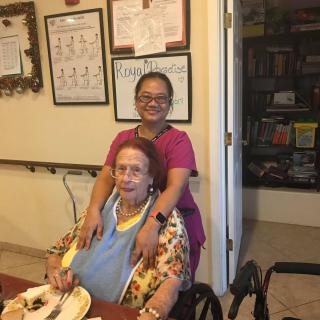 A caregiver and an elderly woman smiling together indoors.