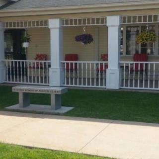 A cozy porch with red chairs and a bench on a sunny day.
