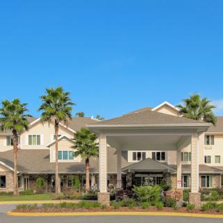 A residential building with palm trees and a grand entrance on a sunny day.