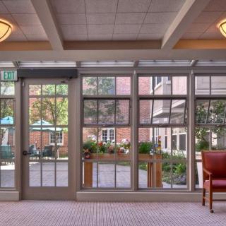 A cozy lobby area with glass doors and windows overlooking an outdoor patio.