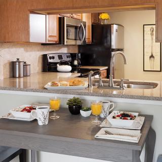 A modern kitchen with a breakfast bar set for two, featuring contemporary appliances and decor.