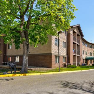 A residential apartment building with trees lining the street on a sunny day.