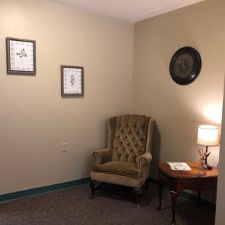 A cozy corner with a tufted chair, side table, and wall decorations.