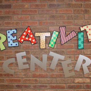 A colorful sign on a brick wall spelling 'Creativity Center'.