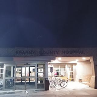A view of the hospital entrance at night, illuminated by outdoor lights with bicycles parked nearby.