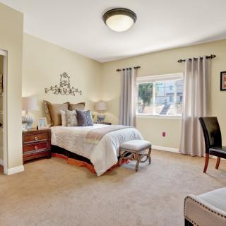 A well-decorated bedroom featuring a bed with pillows, nightstands with lamps, and a window with curtains.