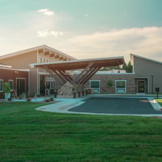 A modern architectural building set in a lush green landscape, basking in the warm glow of sunset.
