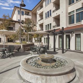 A modern apartment building courtyard featuring a central fountain and outdoor seating area.
